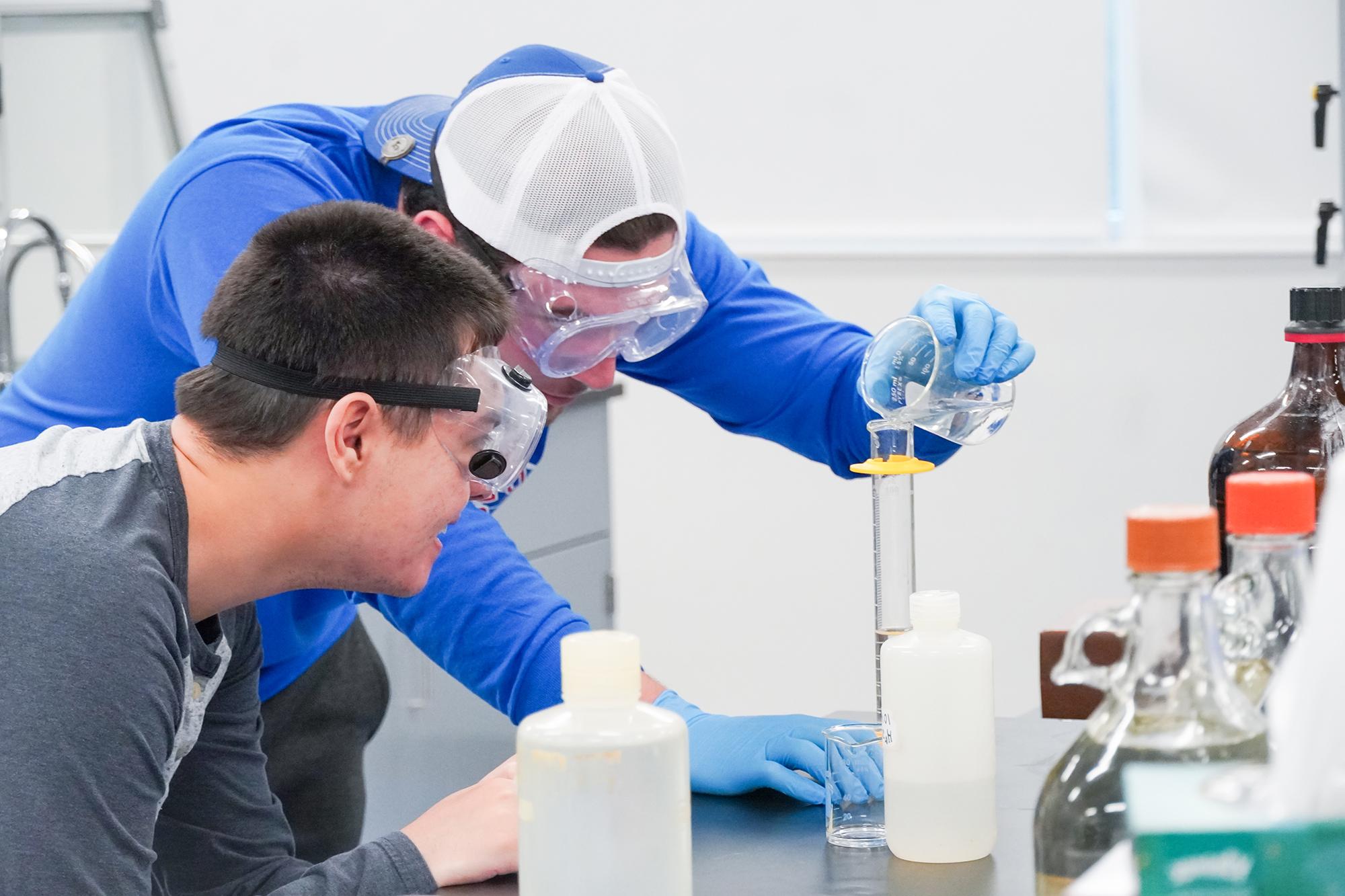 Male scientist holding two flasks with chemicals in them