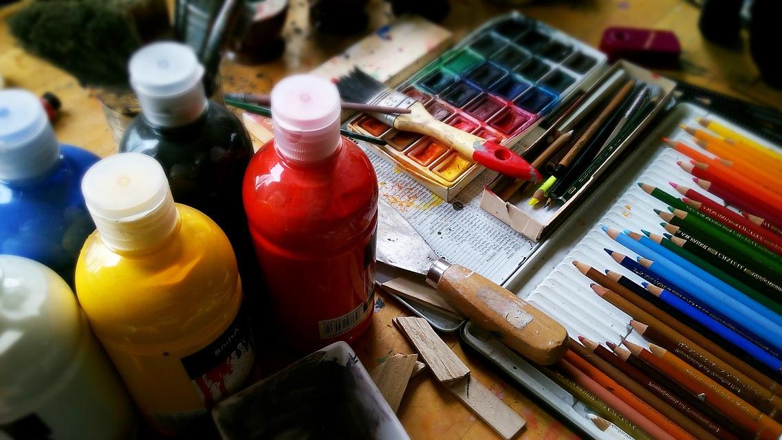 A table with colored pencils and painting supplies on it